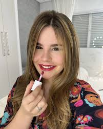 Belonger sorrindo aplicando gloss da Belong Be